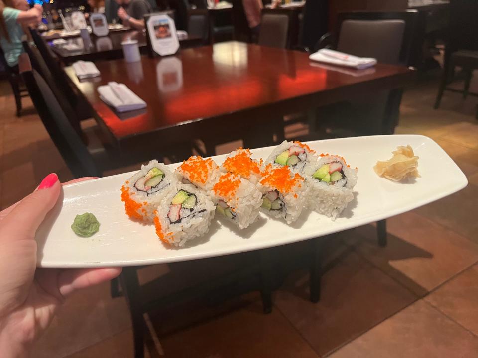 Author holds a plate of eight California rolls with ginger and wasabi