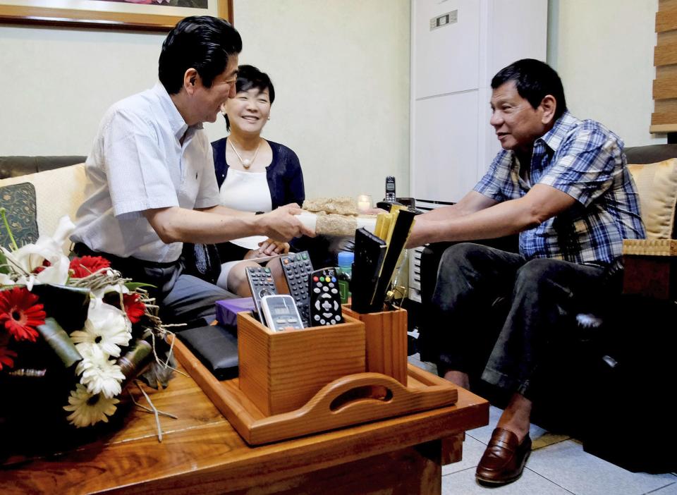 In this photo provided by the Presidential Photographers Division Malacanang Palace, Philippine President Rodrigo Duterte, right, hands a gift to visiting Japanese Prime Minister Shinzo Abe and his wife Akie to the President's residence at Dona Luisa Village in Davao City, Friday, Jan. 13, 2017, in the southern Philippines. Abe capped his two-day official visit to the Philippines by having breakfast with Duterte at his home in Davao city. (Rene Lumawag, Presidential Photographers' Division via AP)