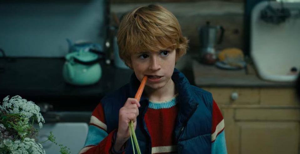 Young Adam taking a bite out of a carrot in "The Adam Project"