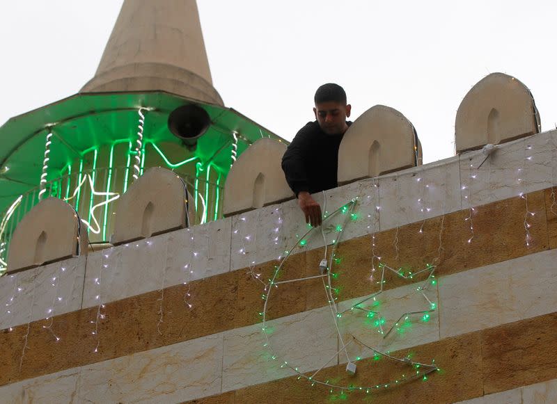 A man hangs decorations ahead of the Muslim holy month of Ramadan on a mosque during a countrywide lockdown over the coronavirus disease (COVID-19) in Beirut