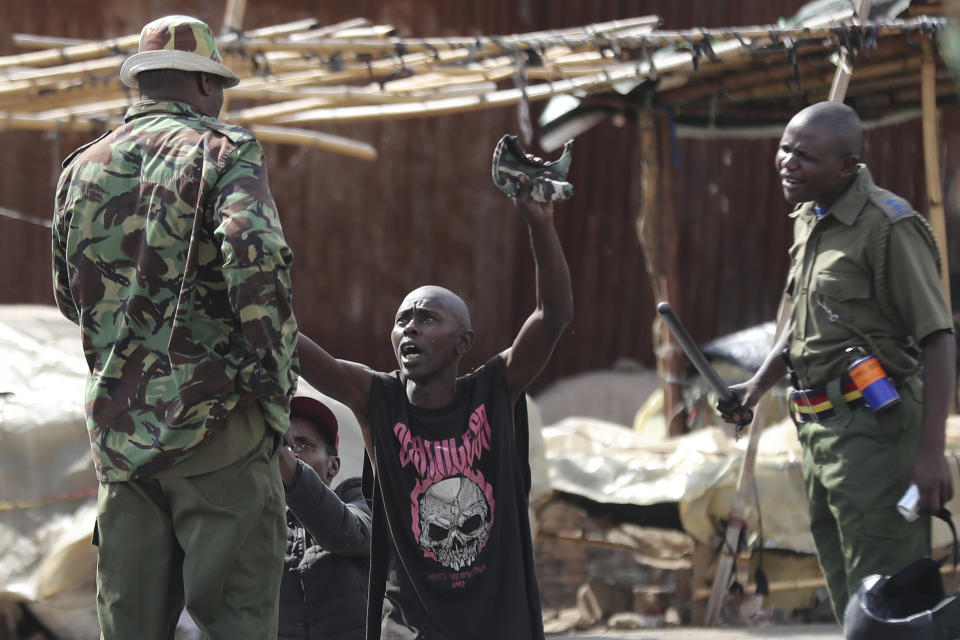 A man gestures to police in Kibera slums as police clash with demonstrators during a protest by supporters of Kenya's opposition leader Raila Odinga over the high cost of living and alleged stolen presidential vote, in Nairobi, Monday, March 20, 2023. (AP Photo/Brian Inganga)