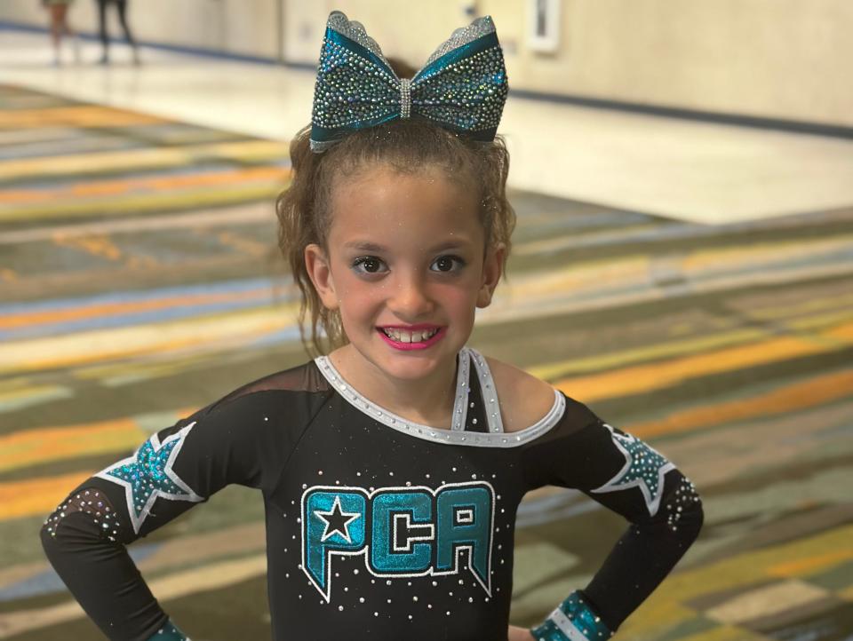 Leah Whitty wearing her cheerleading outfit with a blue bow in her hair.