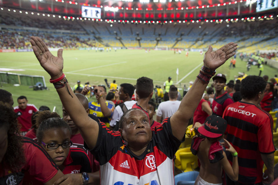 In this May 4, 2014 photo, Maria Boreth de Souza gestures to the sky after making the sign of the cross to give thanks that her team, Flamengo, defeated Palmeiras as she waits for the stadium to clear out before leaving Maracana stadium for home in Rio de Janeiro, Brazil. Souza is equally fanatical about Brazil's national team. "I pray they win the World Cup," she said. (AP Photo/Leo Correa)