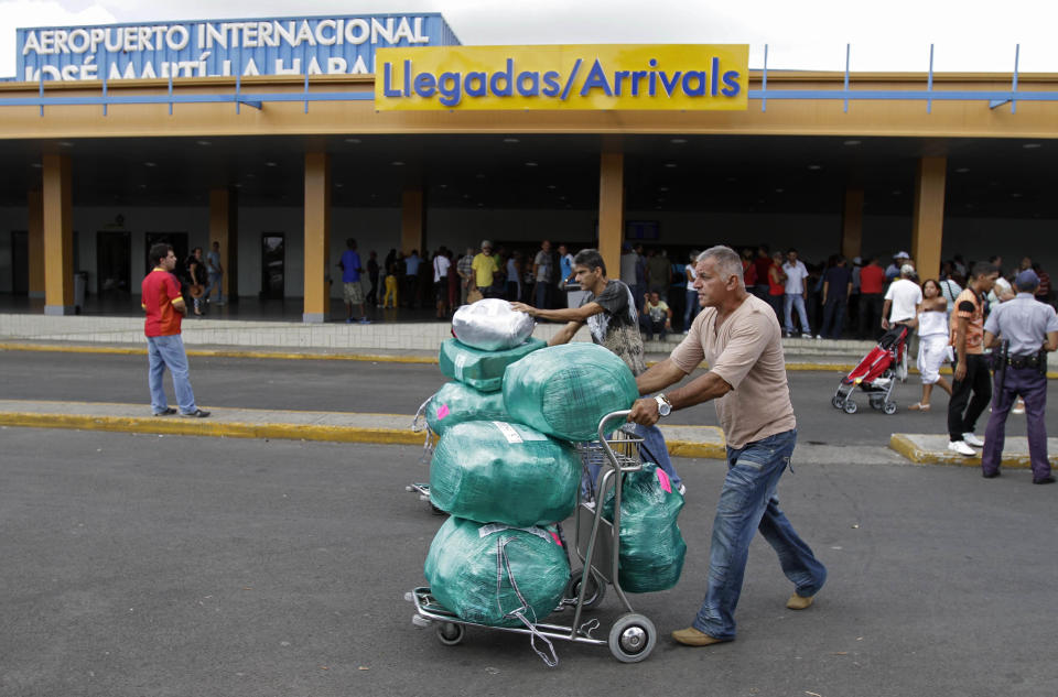 Juan, a Cuban-American man who did not want to give his last name, front, arrives with packages after getting off a flight from the U.S. as his brother, who lives in Cuba, behind, helps him with other packages at the Jose Marti International Airport in Havana, Cuba, Monday, Sept. 3, 2012. A steep hike in customs duties has taken effect in Cuba, catching some air travelers unaware and leaving others irate at the new fees. (AP Photo/Franklin Reyes)