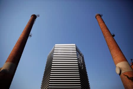 The Smog Free Tower, the world's largest smog vacuum cleaner designed by Dutch artist and innovator Daan Roosegaarde is seen between chimneys as the artist presents his The Smog Free Project at D-751 art zone in Beijing September 29, 2016. REUTERS/Damir Sagolj