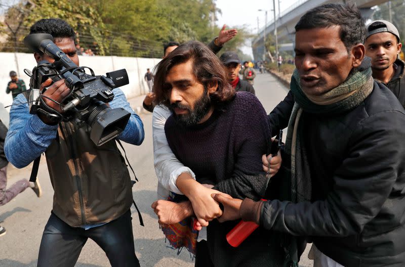 Wounded man is helped after an unidentified man opened fire during a protest against a new citizenship law outside the Jamia Millia Islamia university in New Delhi