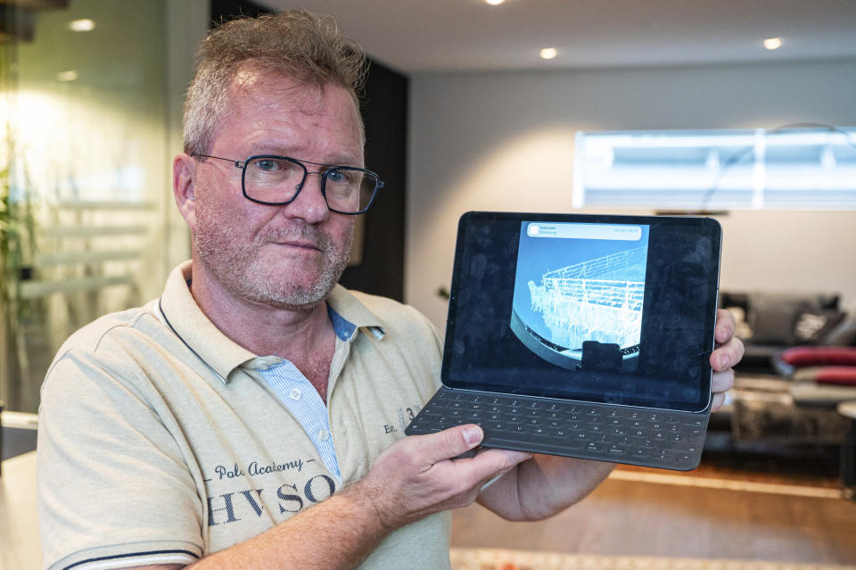 Arthur Loibl, one of the submersible company Oceangate's first customers, holds up a photo of the Titanic, in Straubing, Germany, Wednesday June 21, 2023. As an international search continued for a vessel that disappeared after setting out for the underwater wreckage of the Titanic, Arthur Loibl characterized a dive he made to the site two years ago as a “kamikaze operation.” (Armin Weigel/dpa via AP)