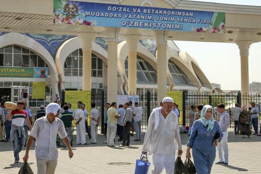 People walk at a central market in Tashkent, Uzbekistan, Tuesday, Aug. 30, 2016. News agencies report a concert marking Uzbekistan's 25th anniversary of independence from the Soviet Union has been cancelled amid uncertainty about the health of the country's hospitalized president. A poster in the back reads 'Beautiful and unique, sacred Motherland, I can sacrifice my life to my Uzbekistan.' (AP Photo)