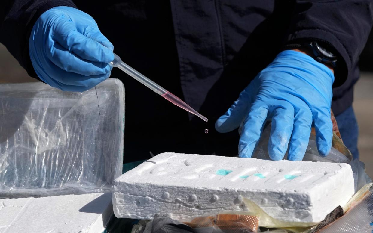 A narcotics officer conducts a chemical analysis to confirm the purity of a cocaine block - AP