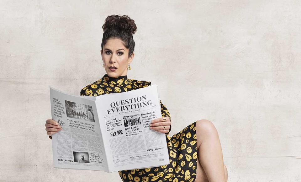 Jan Fran wearing a black and gold dress while holding a newspaper. Photo: supplied.