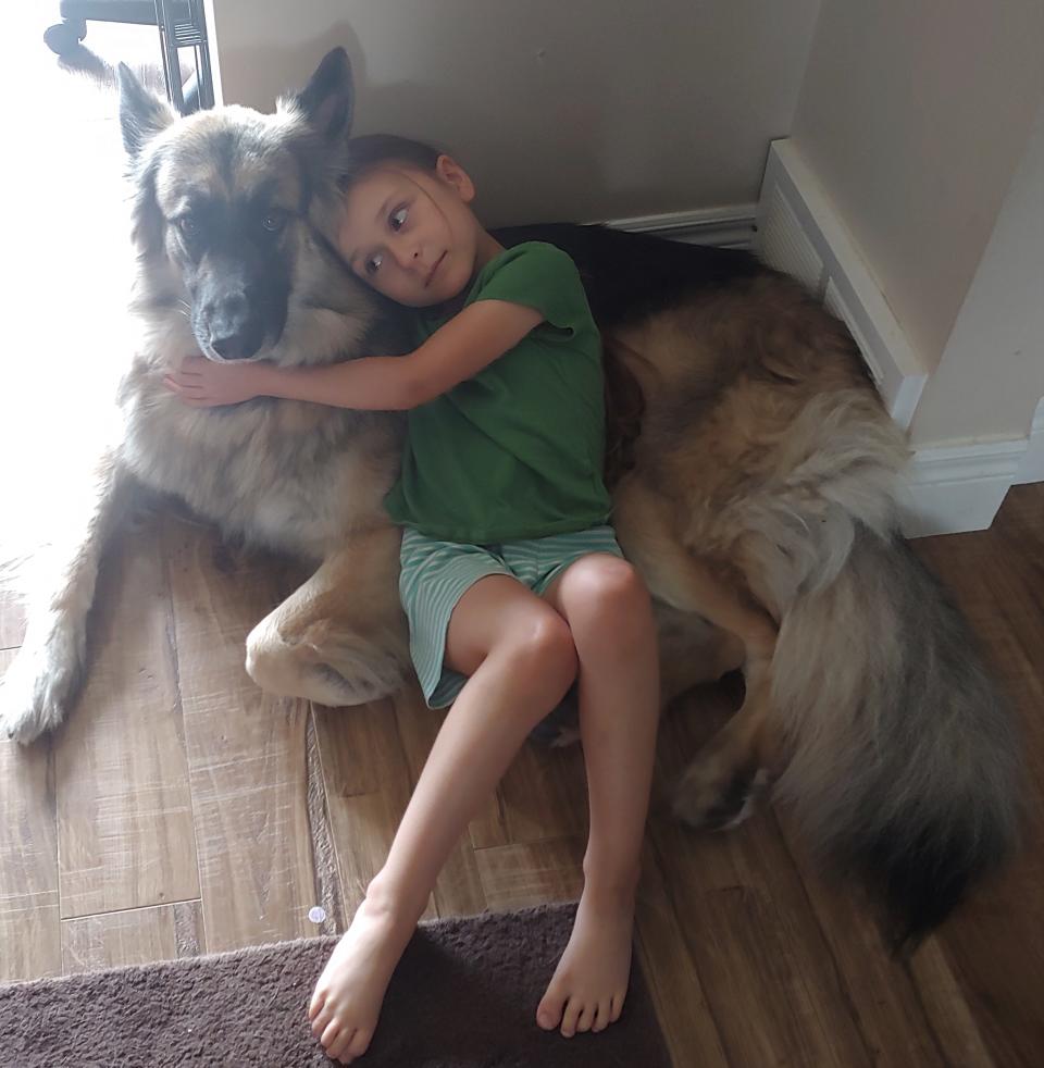 Quintessence Henderson, 5, wearing green t-shirt and green shorts laying and snuggling with pet on floor