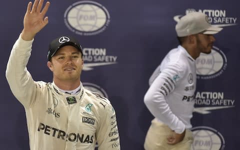 Mercedes AMG Petronas F1 Team's German driver Nico Rosberg (L) waves as he celebrates pole position, as Mercedes AMG Petronas F1 Team's British driver Lewis Hamilton (R) walks away after the qualifying session on September 17, 2016, ahead of the Formula One Grand Prix night race - Credit: AFP/Getty Images