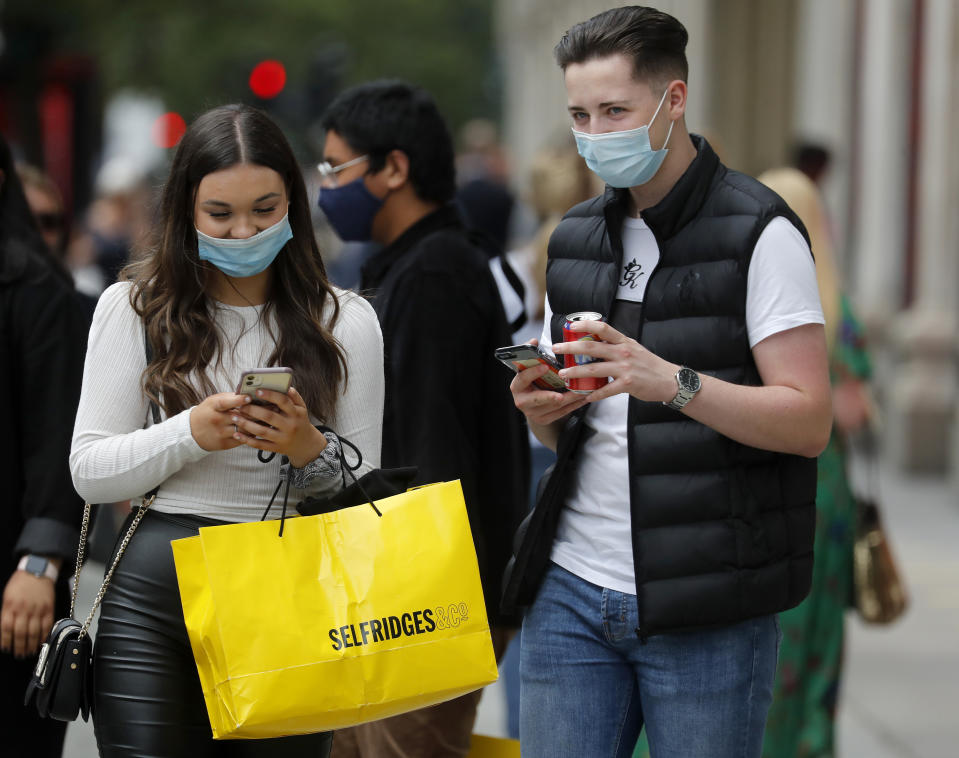 Shoppers wearing protective face masks walk along Oxford Street in London, Tuesday, July 14, 2020.Britain's government is demanding people wear face coverings in shops as it has sought to clarify its message after weeks of prevarication amid the COVID-19 pandemic. (AP Photo/Frank Augstein)