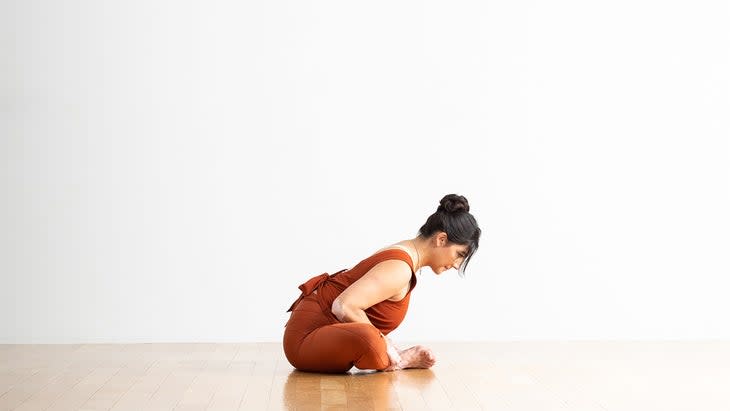 A person demonstrates a modification of Bound Angle Pose (Baddha Konasana) in yoga, bending forward over the legs