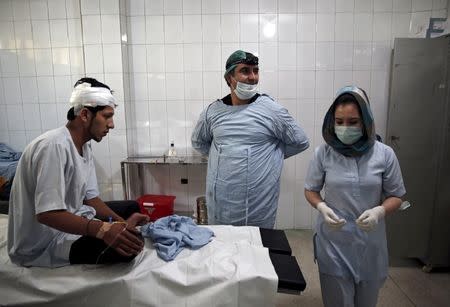 Plastic surgeon Abdul Ghafar Ghayur (C) speaks to a nurse after an operation at Aria City Hospital, in Kabul, Afghanistan August 6, 2015. REUTERS/Ahmad Masood