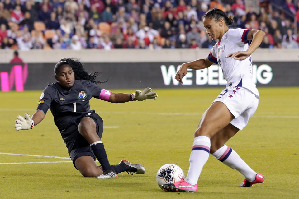 Panama goalkeeper Yenith Bailey (1) defends as U.S. forward Lynn Williams (13) attempts a shot on goal during the first half of a CONCACAF women's Olympic qualifying soccer match Friday, Jan. 31, 2020, in Houston. (AP Photo/Michael Wyke)