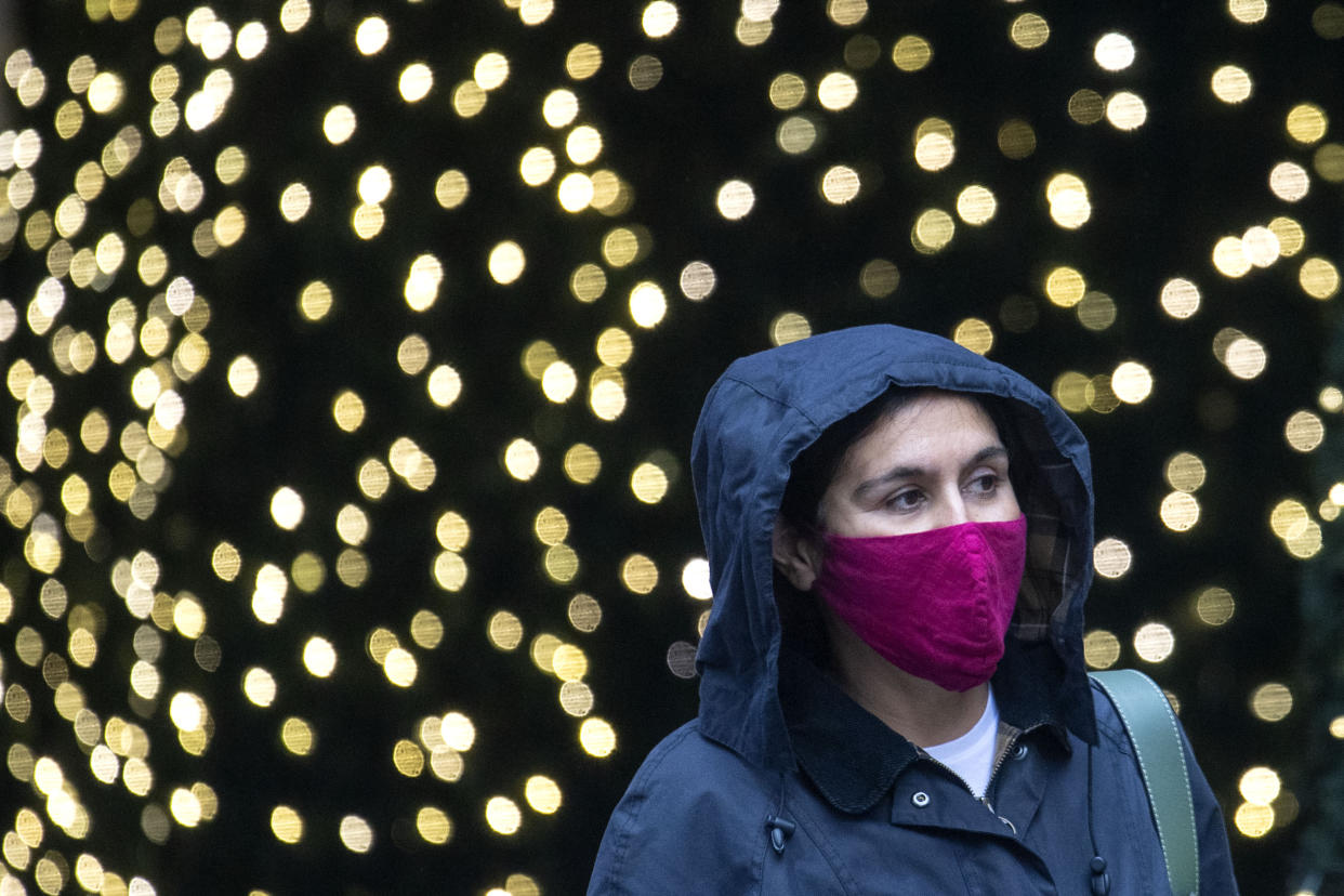 A woman wearing a face mask walks past Christmas lights outside a department store in central London. A new three-tier system of alert levels for England has been implemented following rising coronavirus cases and hospital admissions. (Photo by Dominic Lipinski/PA Images via Getty Images)