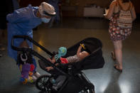 Spanish NGO Open Arms volunteer, Julia Martin, 38, plays with 4-month old Biel, as his father takes a COVID-19 PCR test, at Vilafranca del Penedes in the Barcelona province, Spain, Tuesday, Aug. 11, 2020. Spain is facing another surge in coronavirus infections not even two months after beating back the first wave. (AP Photo/Emilio Morenatti)