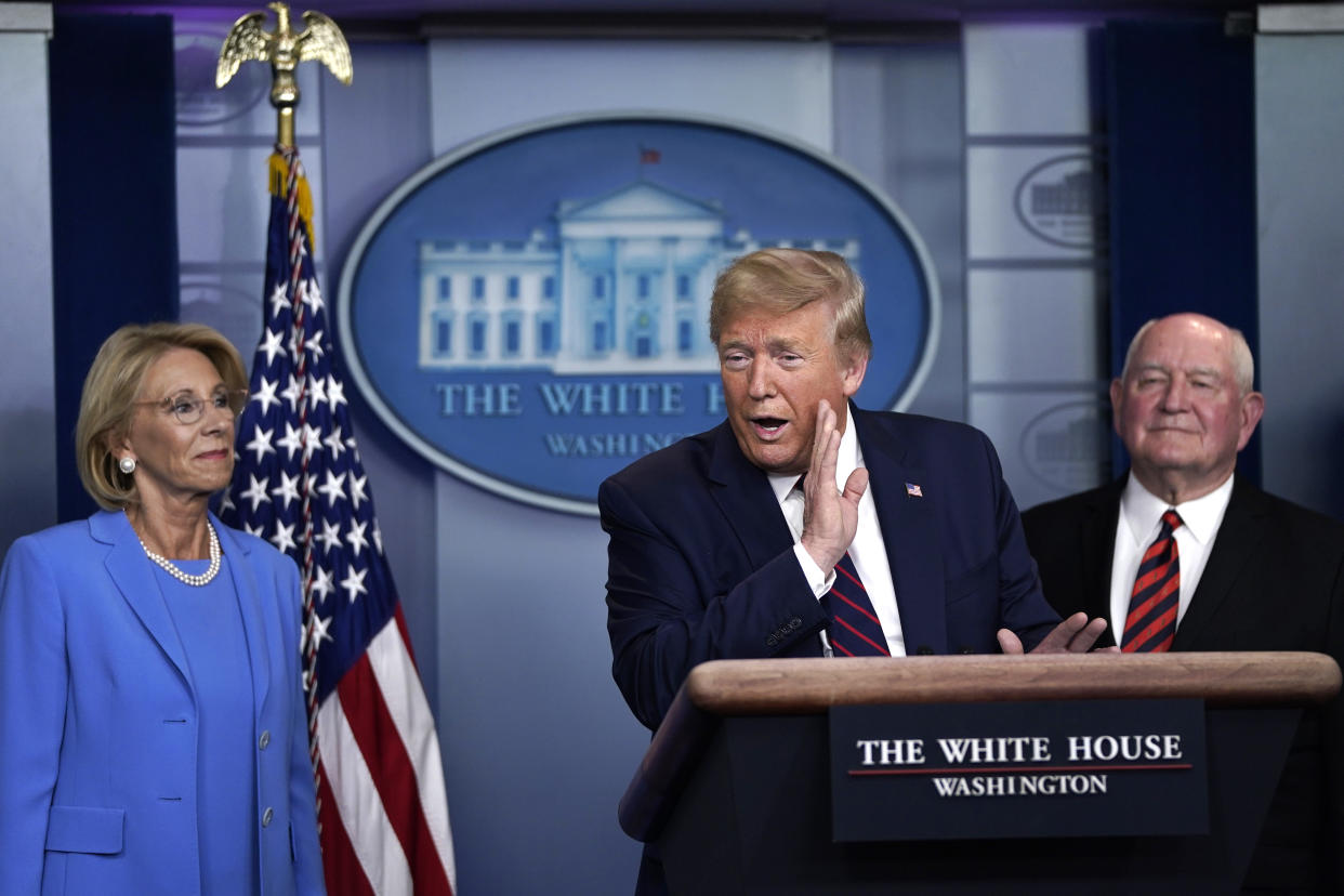 WASHINGTON, DC - MARCH 27:  U.S. President Donald Trump speaks as Secretary of Education Betsy DeVos and Secretary of Agriculture Sonny Perdue look on during a briefing on the coronavirus pandemic in the press briefing room of the White House on March 27, 2020 in Washington, DC. President Trump signed the H.R. 748, the CARES Act on Friday afternoon. Earlier in the day, the U.S. House of Representatives approved the $2 trillion stimulus bill that lawmakers hope will battle the economic effects of the COVID-19 pandemic.  (Photo by Drew Angerer/Getty Images)