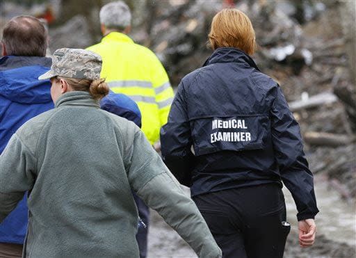 A medical examiner enters the scene at the west side of the mudslide on Highway 530 near mile marker 37  in Arlington, Wash., on Sunday, March 30, 2014. Periods of rain and wind have hampered efforts the past two days, with some rain showers continuing today. Last night, the confirmed fatalities list was updated to 18, with the number of those missing falling from 90 to 30. (AP Photo/Rick Wilking, Pool)