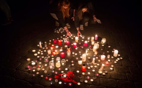 People light candles in tribute to the dead - Credit: Friso Gensch/dpa via AP