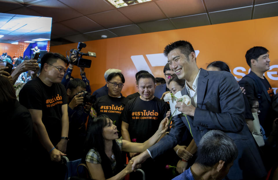 Future Forward Party leader Thanathorn Juangroongruangkit, second right, receives flowers from a supporter in a wheel chair after a Thai court ordered to dissolved his political party in Bangkok, Thailand, Friday, Feb. 21, 2020. Thailand's Constitutional Court on Friday ordered the popular opposition Future Forward Party dissolved, declaring that it violated election law by accepting a loan from its leader. (AP Photo/Gemunu Amarasinghe)