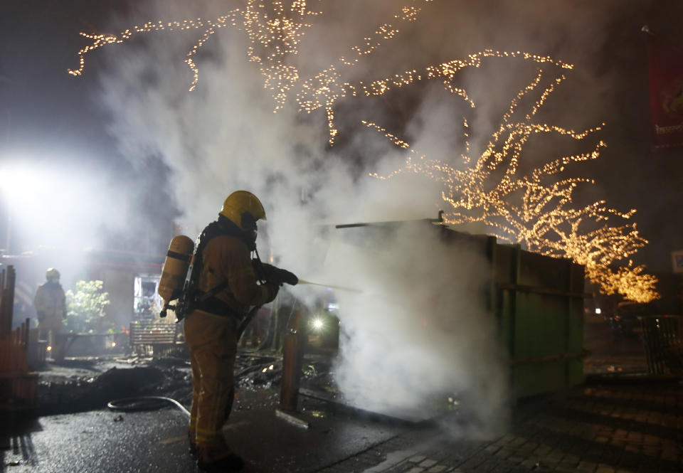 A firefighter extinguishes a container that was set alight during protests against a nation-wide curfew in Rotterdam, Netherlands, Monday, Jan. 25, 2021. The Netherlands Saturday entered its toughest phase of anti-coronavirus restrictions to date, imposing a nationwide night-time curfew from 9 p.m. until 4:30 a.m. in a bid to control the COVID-19 infection rate. (AP Photo/Peter Dejong)