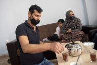 Abdul Salam Al Khawien, 37, serves tea at his apartment in the northern city of Thessaloniki, Greece, Saturday, May 1, 2021. Sundered in the deadly chaos of an air raid, a Syrian family of seven has been reunited, against the odds, three years later at a refugee shelter in Greece's second city of Thessaloniki. (AP Photo/Giannis Papanikos)