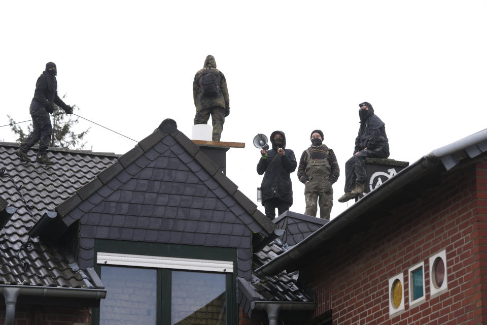 A climate activists stand of a roof top at the village Luetzerath near Erkelenz, Germany, Wednesday, Jan. 11, 2023. Police have entered the condemned village in, launching an effort to evict activists holed up at the site in an effort to prevent its demolition to make way for the expansion of a coal mine. (AP Photo/Michael Probst)