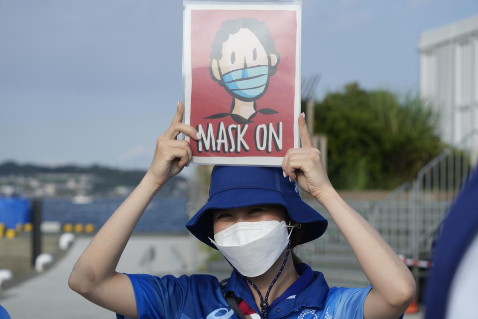 FILE - In this Aug. 1, 2021, file photo, Olympic volunteer Reimi Kusunoki holds up a sign at the Enoshima yacht harbor during the 2020 Summer Olympics in Fujisawa, Japan. Tokyo Olympians are exercising extraordinary discipline against the coronavirus. They are sealed off in a sanitary bubble that has made competition possible but is also squeezing a lot of fun from their Olympic experience. (AP Photo/Gregorio Borgia, File)