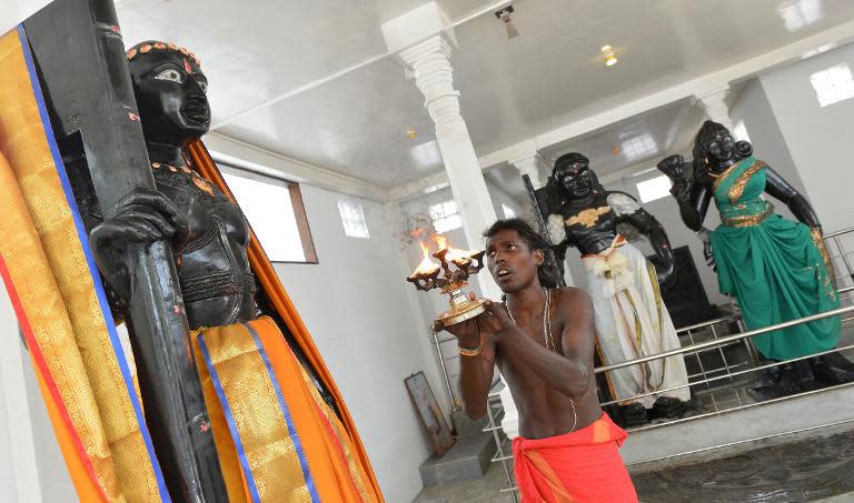 A Hindu priest lights a coconut oil lamp in front of a statue of god Skanda, a deity believed to be a protector of the island, at the Sri Subramaniam temple in Matara on March 7, 2014