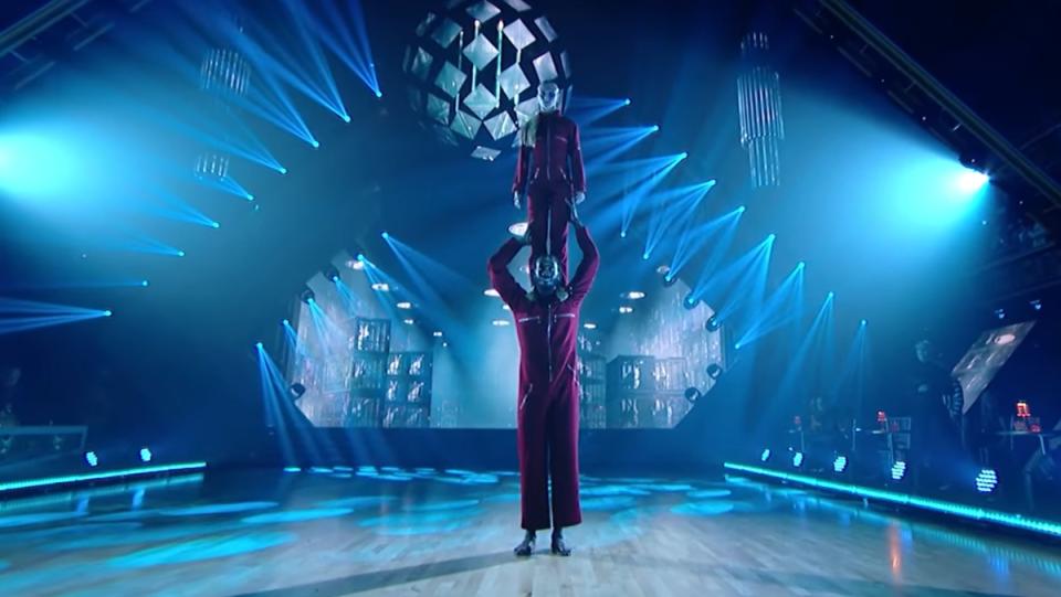 dancing with the stars contestant Iman Shumpert puts his partner on his shoulders while wearing red jumpsuits