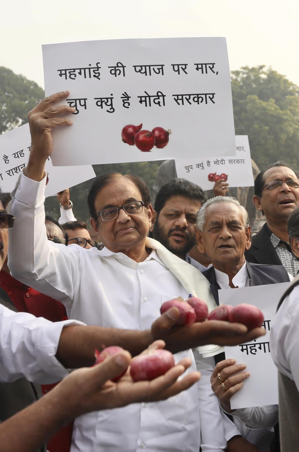 Indian lawmaker and former Finance Minister Palaniappan Chidambaram, center, holds a placard that reads "Why is the Modi government silent on the rise of onion prices, participates in a protest against the rise in onion prices, outside the Indian parliament in New Delhi, India, Thursday, Dec. 5, 2019. The former Indian finance minister just released on bail in a bribery case has joined a protest of the government’s economic policies, which are being blamed for India’s slowest economic growth in six years. (AP Photo/Manish Swarup)