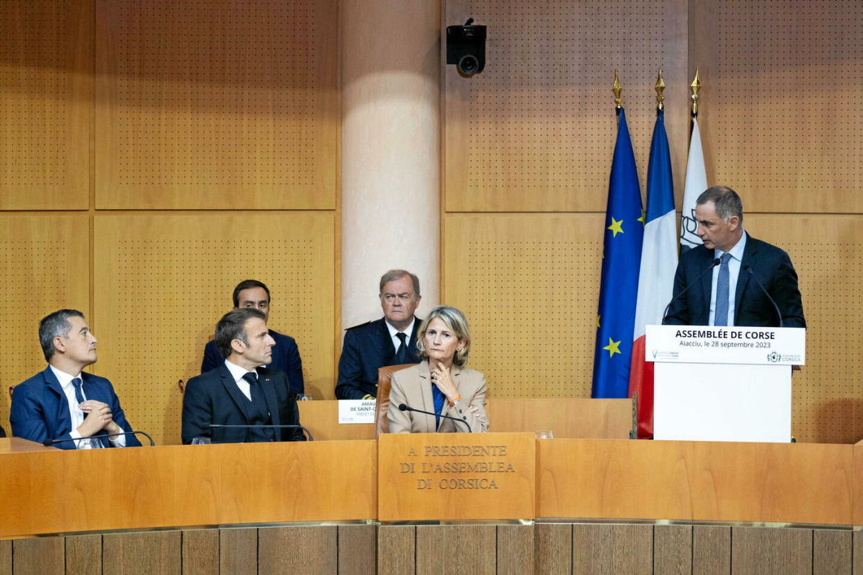 Gérald Darmanin, le ministre de l'Intérieur, et le président Emmanuel Macron, tous deux assis à gauche, ont été accueillis en septembre 2023 à l'assemblée de Corse par Gilles Simeoni, ici debout.  - Credit:Raphael Lafargue/Pool/Sipa