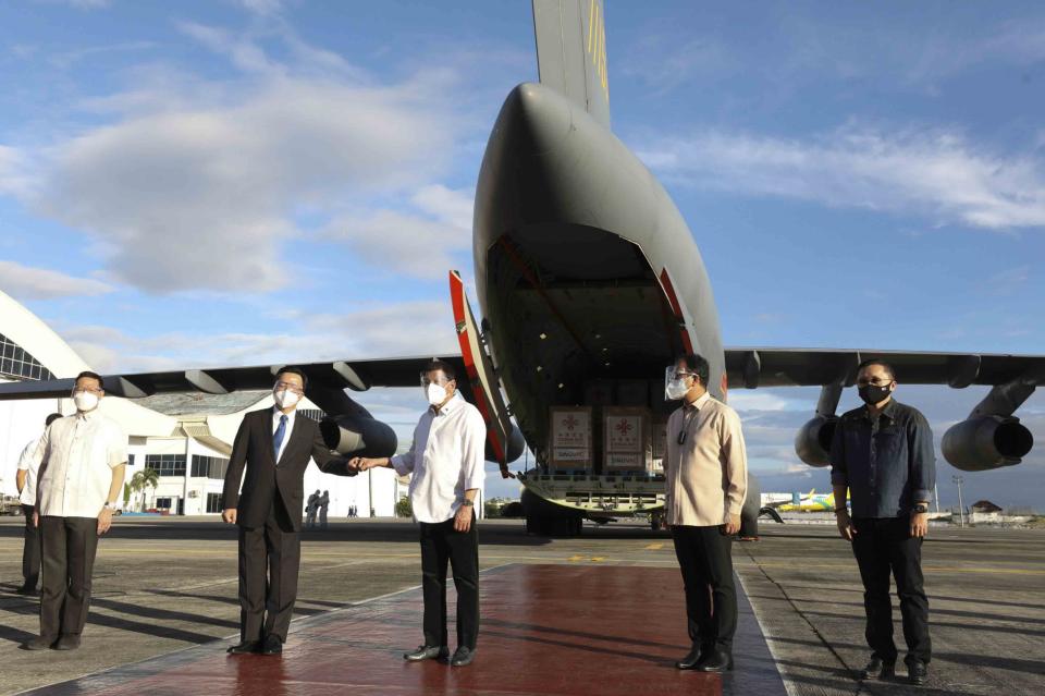 In this photo provided by the Malacanang Presidential Photographers Division, Philippine President Rodrigo Duterte, third from left, poses with Chinese Ambassador to the Philippines Huang Xilian, second from left, as they stand in front of a Chinese military plane carrying Sinovac vaccines from China at the Villamor Air Base in Manila, Philippines on Sunday Feb. 28, 2021. The Philippines received its first batch of COVID-19 vaccine Sunday, among the last in Southeast Asia to secure the critical doses despite having the second-highest number of coronavirus infections and deaths in the hard-hit region. (Toto Lozano/ Malacanang Presidential Photographers Division via AP)