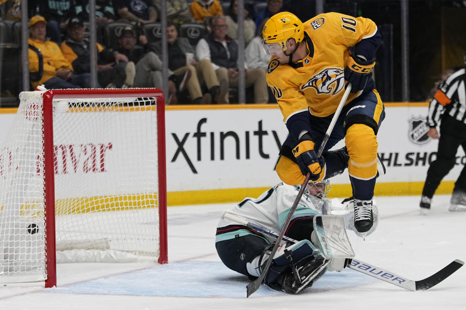 Nashville Predators center Colton Sissons (10) leaps over Seattle Kraken goaltender Philipp Grubauer after scoring a goal during the second period of an NHL hockey game Thursday, Oct. 12, 2023, in Nashville, Tenn. (AP Photo/George Walker IV)