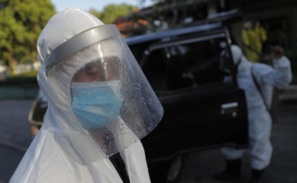 A Sri Lankan funeral service worker in protective suit stands after the cremation of a COVID-19 victim at a cemetery in Colombo, Sri Lanka, Friday, Jan. 22, 2021. Sri Lanka on Friday approved the Oxford-AstraZeneca vaccine for COVID-19 amid warnings from doctors that front-line health workers should be quickly inoculated to stop the system from collapsing. (AP Photo/Eranga Jayawardena)
