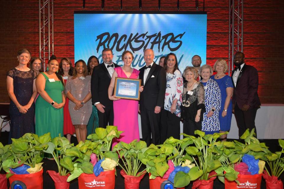 Muscogee County School District 2024 Teacher of the Year Christie Akers of Northside High School poses with her certificate along with Muscogee Educational Excellence Foundation chairman Josh Reynolds, left, and MCSD superintendent David Lewis, surrounded by previous MCSD Teacher of the Year award winners, during MEEF’s Teacher of the Year gala May 9, 2024, in the Columbus Convention & Trade Center.