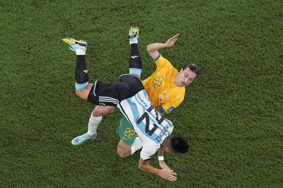 Argentina's Lautaro Martinez falls while battling for the ball with Australia's Jackson Irvine during the World Cup round of 16 soccer match between Argentina and Australia at the Ahmad Bin Ali Stadium in Doha, Qatar, Saturday, Dec. 3, 2022. (AP Photo/Pavel Golovkin)