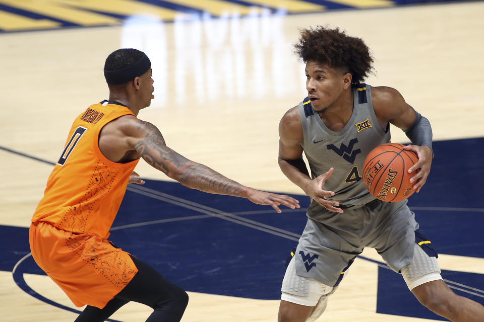 West Virginia guard Miles McBride (4) is defended by Oklahoma State guard Avery Anderson III (0) during the second half of an NCAA college basketball game Saturday, March 6, 2021, in Morgantown, W.Va. (AP Photo/Kathleen Batten)