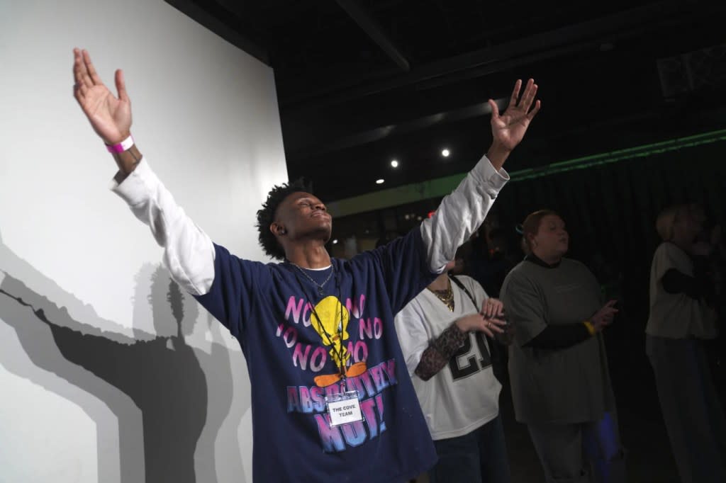 Jeremiah Manley, left, and other attendees at The Cove, an 18-and-up, pop-up Christian nightclub, raise their arms in worship on Saturday, Feb. 17, 2024, in Nashville, Tenn. (AP Photo/Jessie Wardarski)