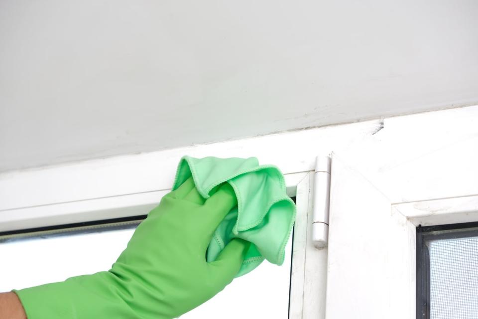 A man washes a glass window and a plastic frame with a cloth