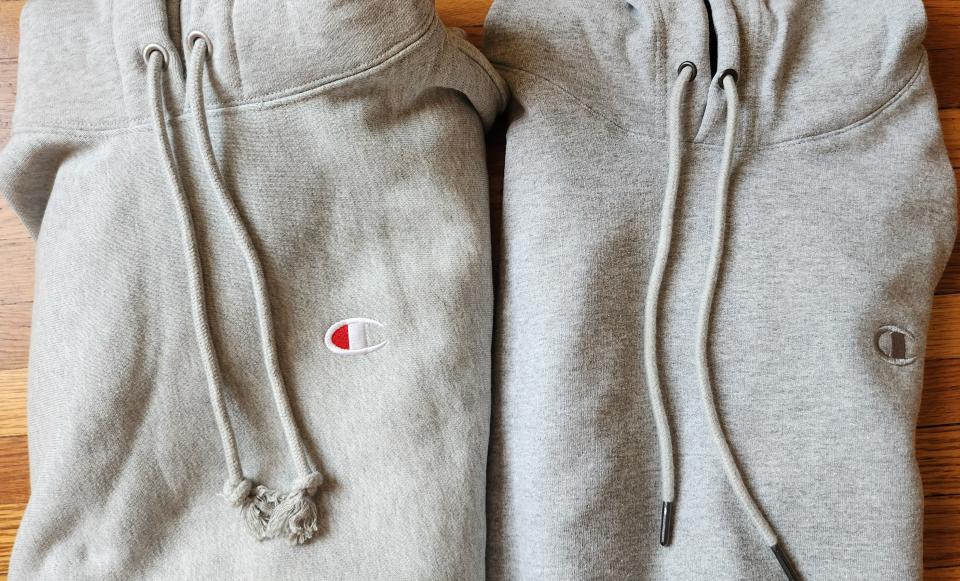The drawstrings and emblems of two champion hoodies side by side on a wood floor