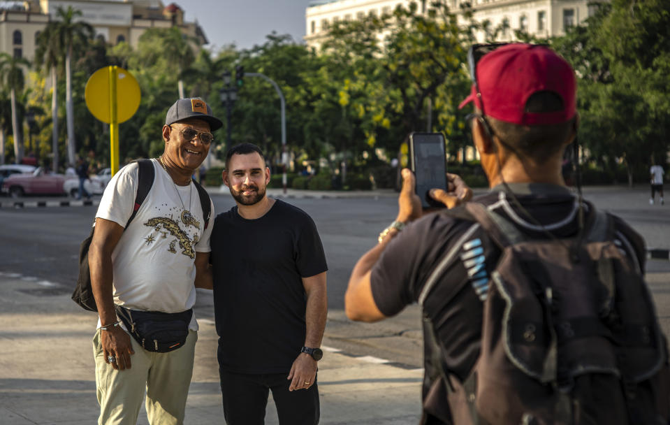 Elián González, en el centro, posa con un peatón que le pidió una foto mientras da una entrevista en La Habana, Cuba, el jueves 27 de junio de 2023. (AP Foto/Ramón Espinosa)