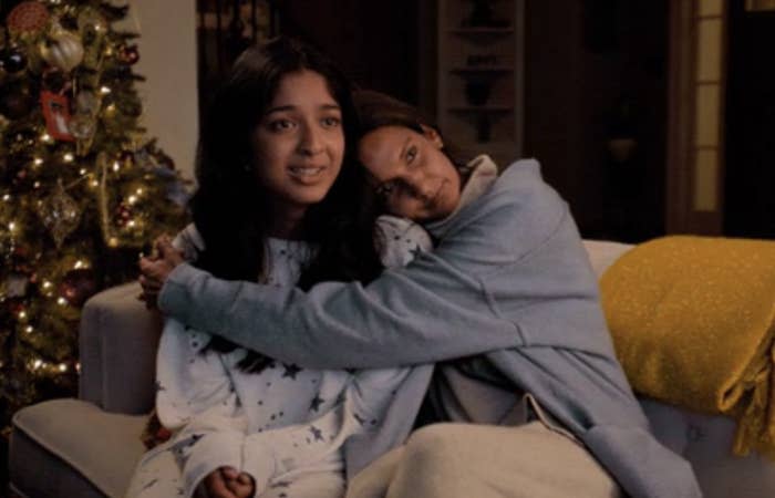 Two characters from a film or show embracing on a couch, with a Christmas tree in the background