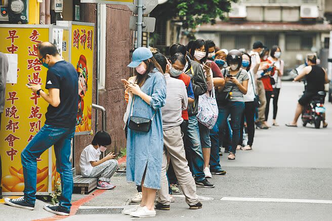 民眾5日排隊搶買快篩試劑，許多藥局供不應求。一名孩童不忍久站，蹲坐在階梯上休息。（郭吉銓攝）