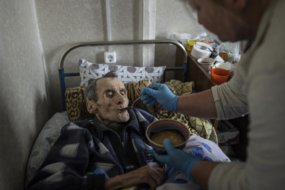 Mykola Svyryd, 70, is fed by a nurse in a shelter for injured and homeless people in Izium, Ukraine, Monday, Sept. 26, 2022. A young Ukrainian boy with disabilities, 13-year-old Bohdan, is now an orphan after his father, Mykola Svyryd, was taken by cancer in the devastated eastern city of Izium. (AP Photo/Evgeniy Maloletka)