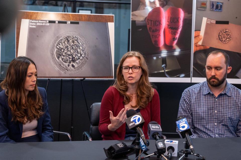 Three people sit at a table with microphones.