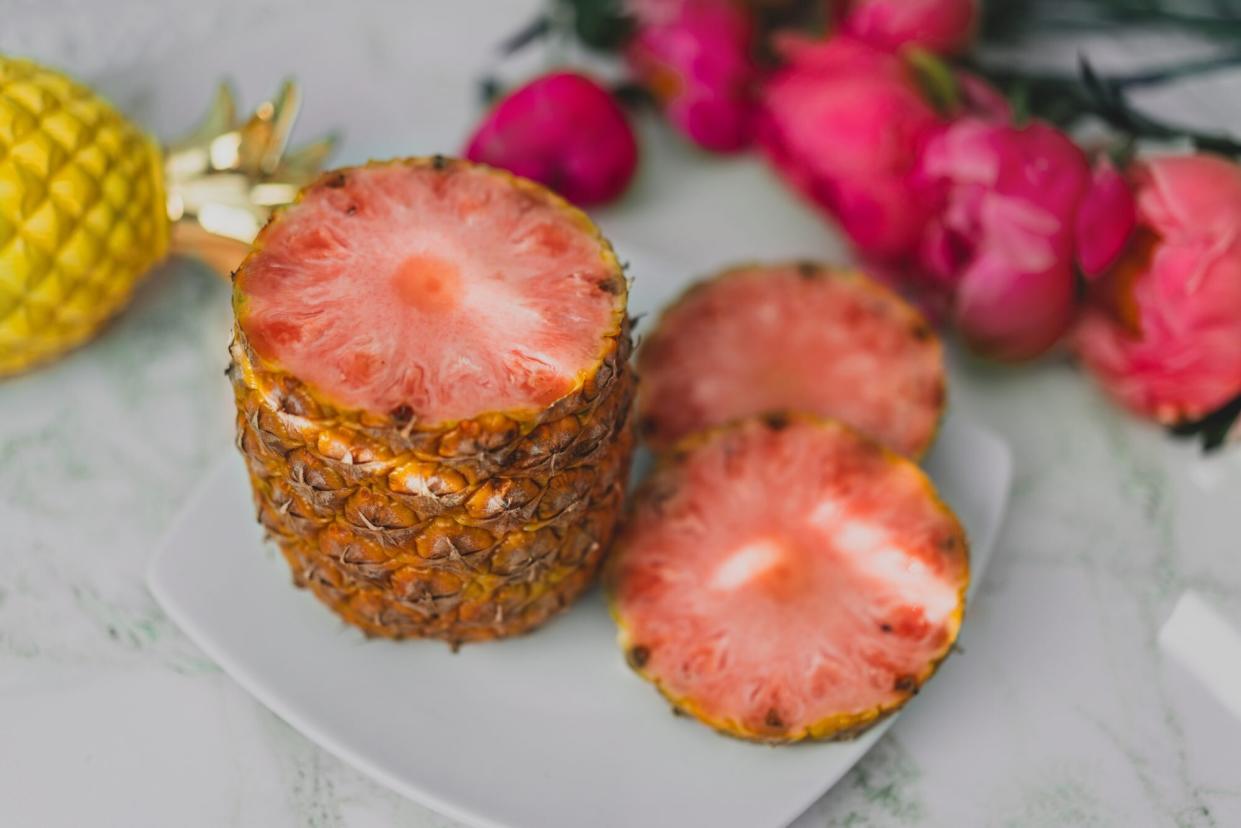 sliced pink pineapple on plate with pink flowers