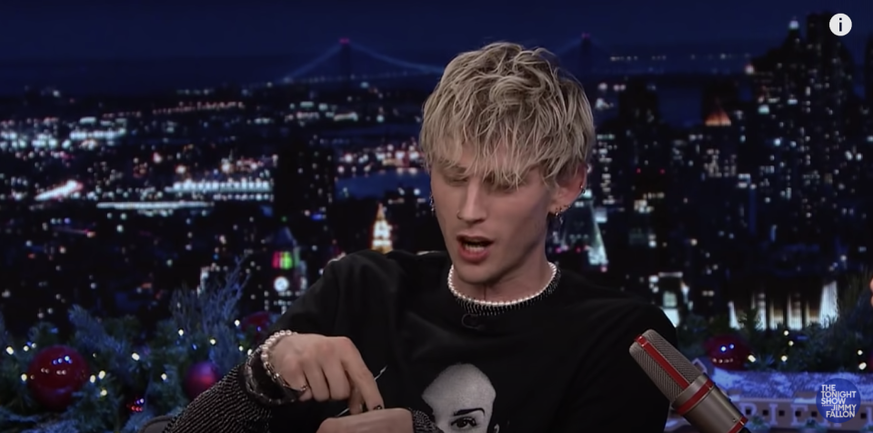 MGK pointing to his hand where the knife got stuck